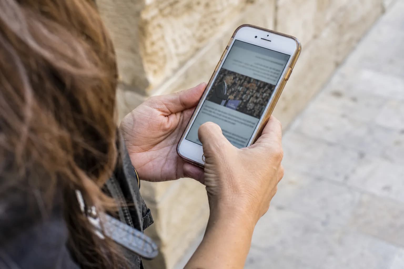 אישה מעיינת בטלפון נייד עם הודעת קמפיין פוליטי ברחוב בירושלים