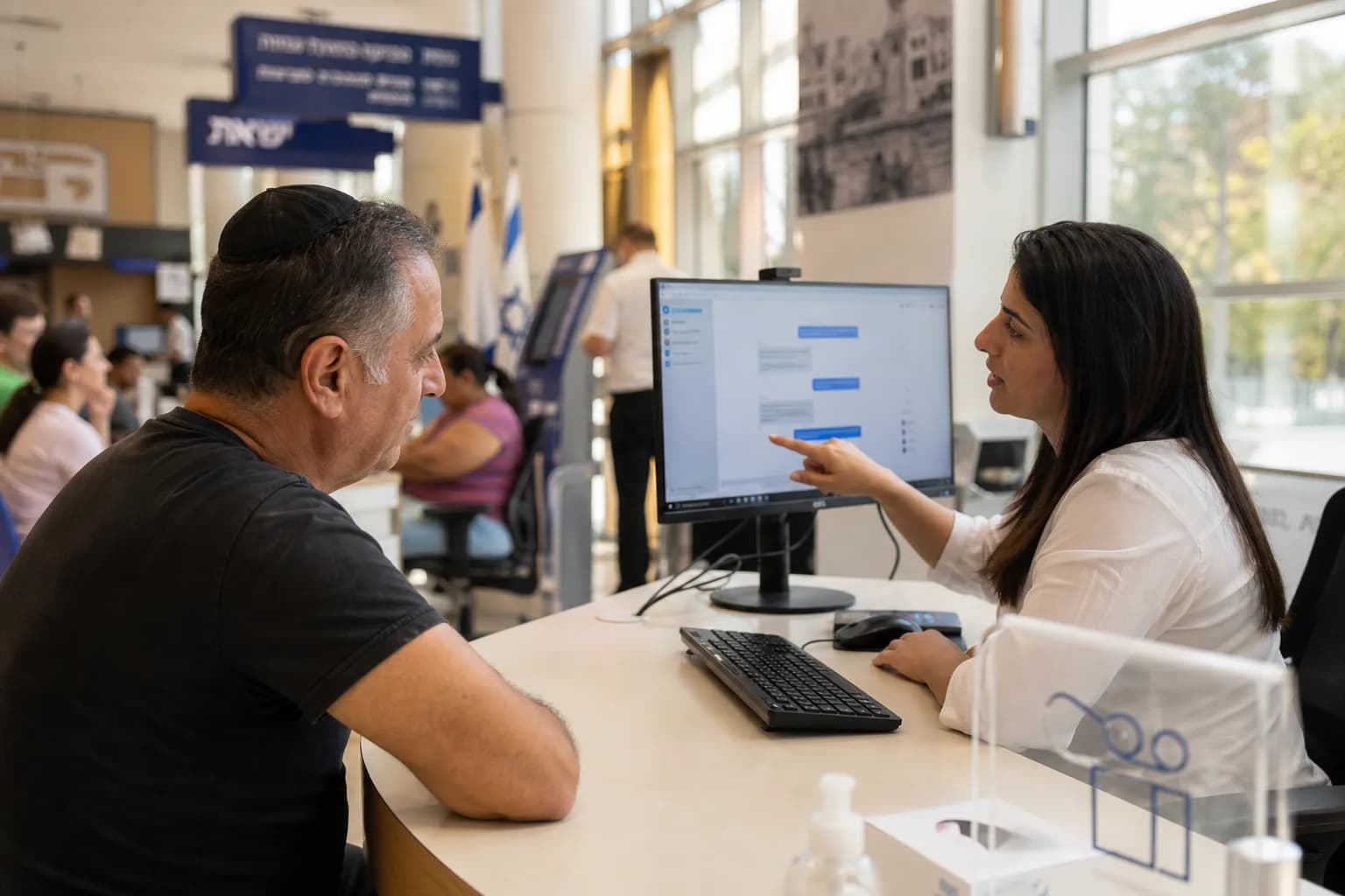 תושב מקבל שירות במרכז שירות עירוני מול מסך עם ממשק צ'אט דיגיטלי
