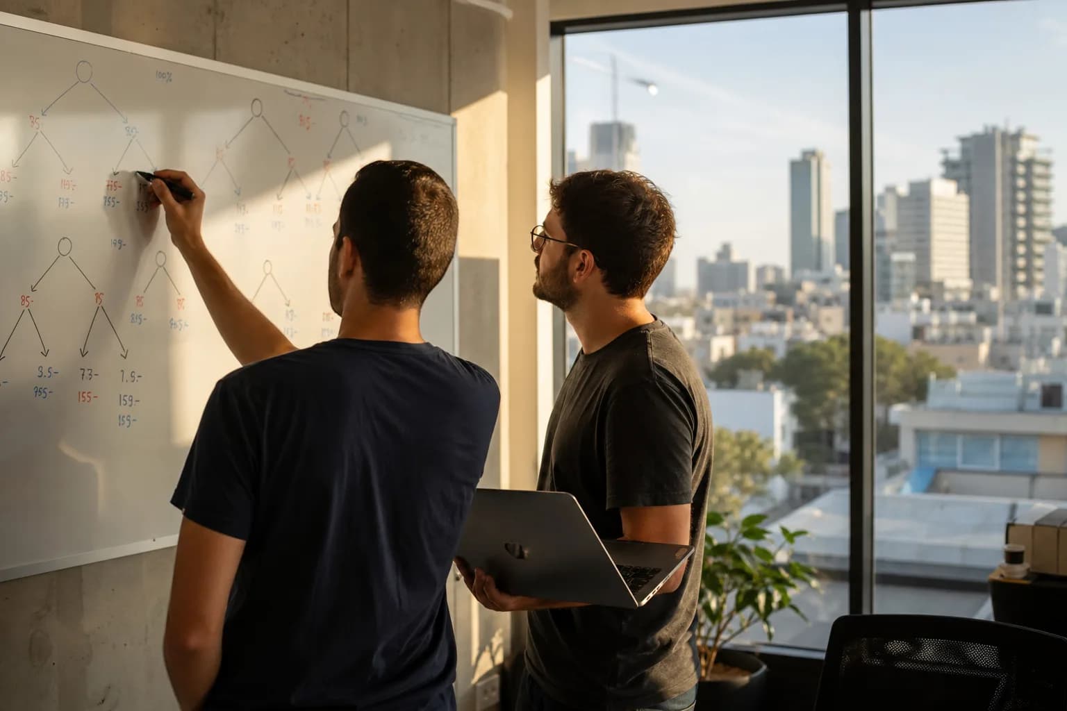 שני מהנדסים בסטארטאפ תל אביבי משרטטים עץ החלטה על לוח מחיק לבחירת מודל שפה