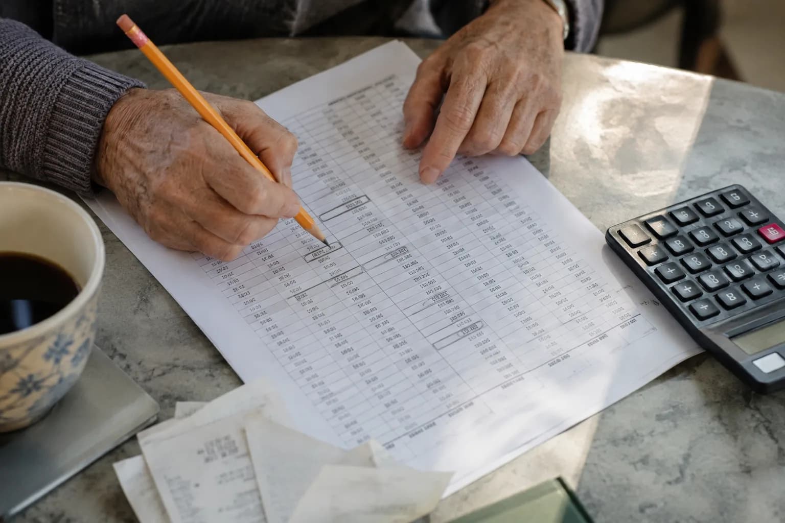 מבט מלמעלה על שולחן בדיקה עם גיליון מודפס של נתונים סינתטיים, שורות מסומנות בעיפרון ומחשבון