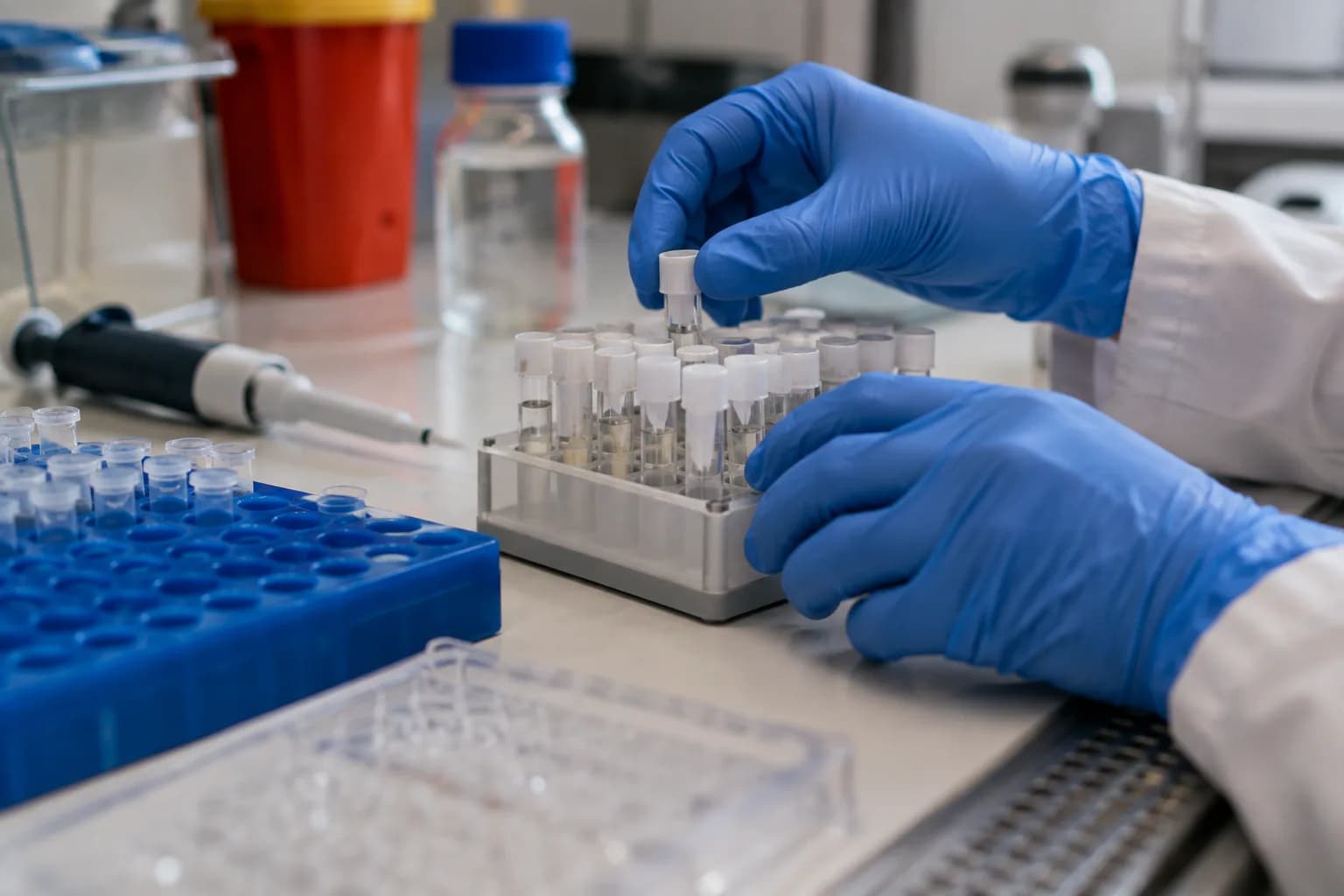 ידיים בכפפות מסדרות מבחנות DNA במעמד על שולחן מעבדה, לצד פיפטה ומגש דגימות